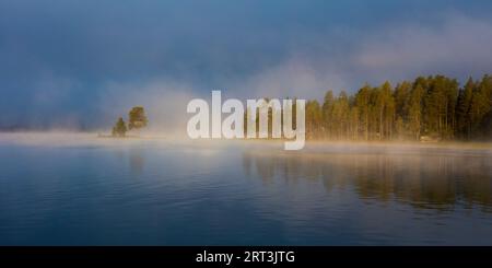 Panoramaaussicht auf die nebelige Herbstmorgendlandschaft am Isteren-See in Engerdal kommune, Norwegen, Skandinavien. Stockfoto