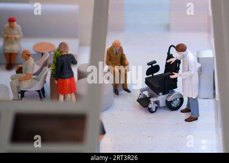 Personen in der Lobby der Klinik mit Rollstuhl für den Patienten Stockfoto