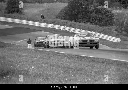 Die Autos fahren auf der Trans am 1969 in Watkins Glen Rennstrecke in New York State über die Kurve 3 bergauf Stockfoto