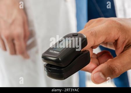 Finger eines asiatischen Erwachsenen aus Indien mit Pulsoxymeter in der Arztpraxis. Stockfoto