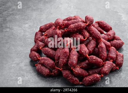 Mini-Salami-Würstchen auf grauem Hintergrund Stockfoto