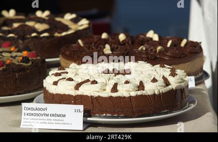 Konditorstand mit Variationen von nicht gebackenen ROHEN Kuchen, Schokoladenkuchen mit Kokoscreme im Vordergrund, Nahaufnahme ohne Menschen auf dem Bauernmarkt. Stockfoto