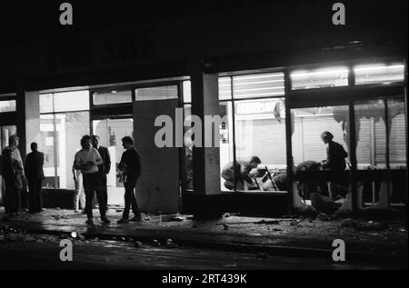 Toxteth stößt 1981 GB auf. Gruppe junger Erwachsener, die in der Nacht der Unruhen aus Geschäften plündern, die in Brand gesetzt wurden. Toxteth, Liverpool 8, England um den 1980. Juli HOMER SYKES Stockfoto