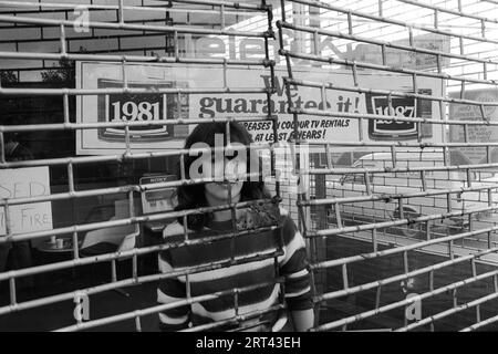 Toxteth Riot, Großbritannien 1981 am Morgen nach den Unruhen, ein Arbeiter hinter dem Metallgrill, der den Laden beschützt, der während der Unruhen nicht geplündert worden war. Liverpool 8 Lancashire HOMER SYKES im Juli 1980 Stockfoto