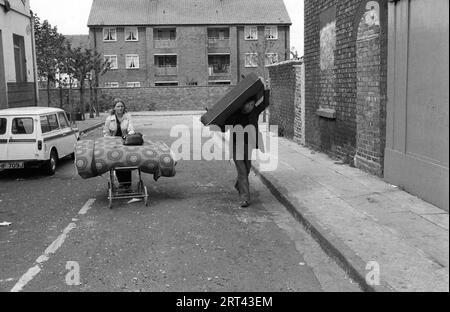 Toxteth Riots 1981 UK. Am Morgen nach der Nacht der Unruhen, ein lokales Paar hilft sich selbst zu einem Bettgestell und Matratze aus einem ausgebrannten geplünderten Geschäft. Sie plündern. Toxteth, Liverpool, Lancashire England um den Juli 1980 HOMER SYKES Stockfoto