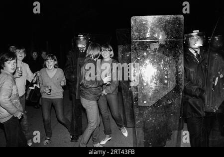 Toxteth Riots 1980s. Polizei in Aufruhr-Kleidung und Schilden. Lokale Jugendliche, Teenager hängen herum und genießen die Aufregung des Aufstands. Toxteth, Liverpool, England Juli 1981 HOMER SYKES Stockfoto