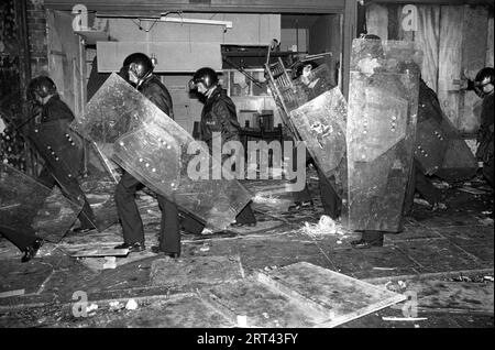 Toxteth wütet in den 1980er Jahren Gebäude wurden in Brand gesetzt, Polizei mit Schilden geht durch ein geplündertes Gebäude. Toxteth, Liverpool, England Juli 1981 HOMER SYKES Stockfoto