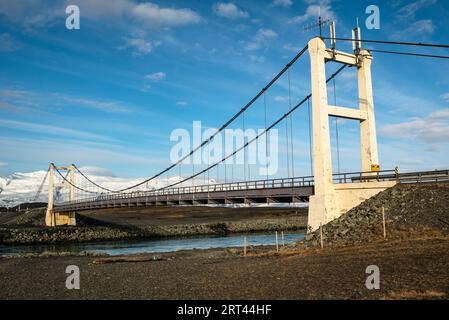 Die berühmte Hängebrücke der Route 1 / Hringvegur (Ringstraße) über den Fluss, der die Jökulsárlón-Gletscherlagune mit dem Atlantischen Ozean verbindet Stockfoto