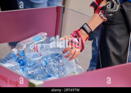 Hand einer Frau, die eine Flasche Wasser aus einem Mülleimer aufnimmt - Moskau, Russland, 05. September 2023 Stockfoto