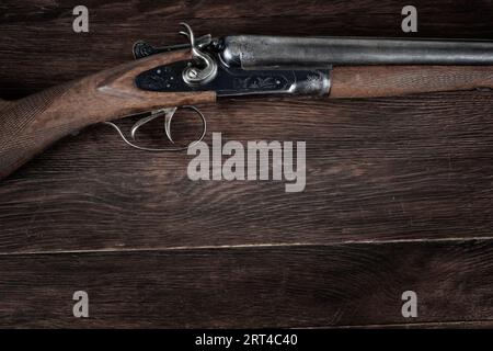 Antike 12-Gauge-Schrotflinte mit glattem Loch auf Holztisch. Stockfoto