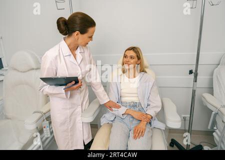 Krankenschwester oder Arzt, der mit dem Patienten spricht, während er ihn auf den Infusionstropfen im Krankenhaus vorbereitet Stockfoto