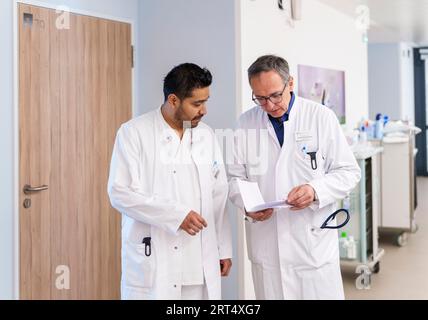 Bad Kreuznach, Deutschland. 30. August 2023. José Jiménez (l), ärztlicher Facharzt für Geriatrie Rheinhessen-nahe, und Jochen Heckmann, ärztlicher Direktor für Geriatrie-Fachklinik Rheinhessen-nahe, sprechen auf der Station miteinander. Mit dem Programm „Specialized!“, der Bundesagentur für Arbeit, soll dem Fachkräftemangel im medizinischen Bereich entgegengewirkt werden. Die geriatrische Fachklinik Rheinhessen-nahe beschäftigt unter anderem seit 2022 einen Arzt aus Mexiko-Stadt. (An dpa 'Ärzte und Krankenschwestern aus dem Ausland, um Fachkräftemangel zu lindern') Credit: Andreas/dpa/Alamy Live News Stockfoto