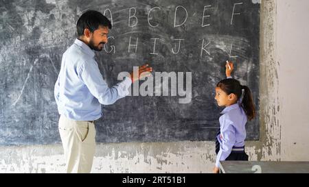 Indischer Lehrer unterrichtet ländliche Schüler im Klassenzimmer, typische Szene in einer ländlichen oder kleinen Dorfschule in Indien Stockfoto