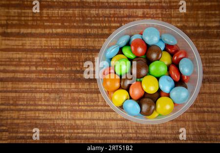 Bunte Schokoladenbonbons auf hölzernem Hintergrund, Draufsicht Stockfoto