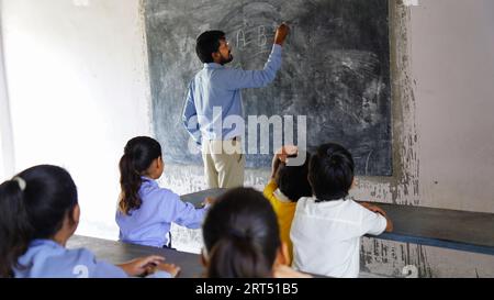 Indischer Lehrer unterrichtet ländliche Schüler im Klassenzimmer, typische Szene in einer ländlichen oder kleinen Dorfschule in Indien Stockfoto