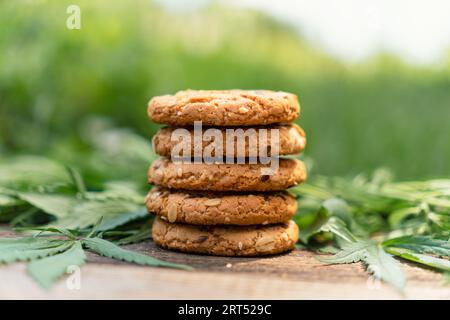 Marihuana-Blatt und Süßigkeiten auf Holztisch. Cannabisblüten und Kekse schließen sich an. Hanf-Erholung, Canna-Küche, Zeitvertreib, Legalisierungskonzept. Kochgeschirr Stockfoto