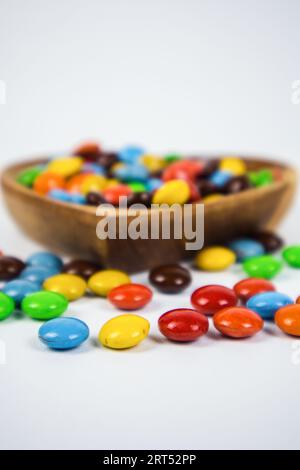 Haufen bunte Schokoladenbonbons in einer Holzschale auf weißem Hintergrund Stockfoto