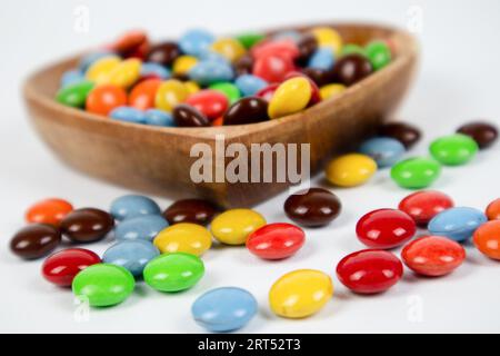 Haufen bunte Schokoladenbonbons in einer Holzschale auf weißem Hintergrund Stockfoto