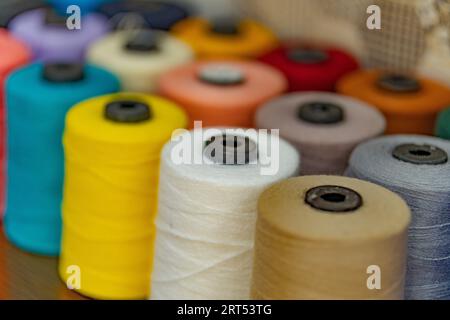 Buntes Garn auf Spule, Schlauch, Baumwolle, Wolle, Leinenfaden. Bunte Fadenspule Hintergrund, Nahaufnahme. Mehrfarbige Fäden zum Nähen und Nähen Stockfoto