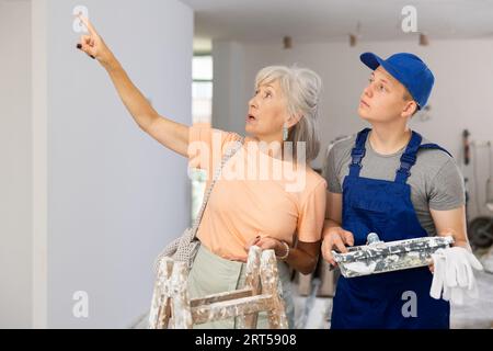 Seniorin spricht mit Teenager-Jungen über Arbeitsdetails an Baustellen Stockfoto