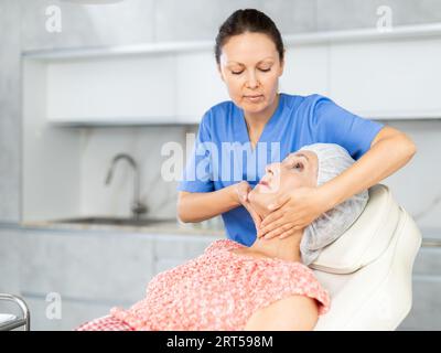 Erfahrener Arzt, der eine Gesichtsmassage an einen Reifen Patienten durchführt Stockfoto