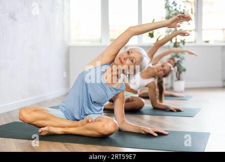 Ältere Frau, die Asana Parsva Sukhasana in Lotusstellung dehnt Stockfoto