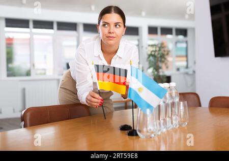 Junge Dame setzt Miniaturen-Flaggen von Argentinien und Deutschland für internationale Verhandlungen Stockfoto