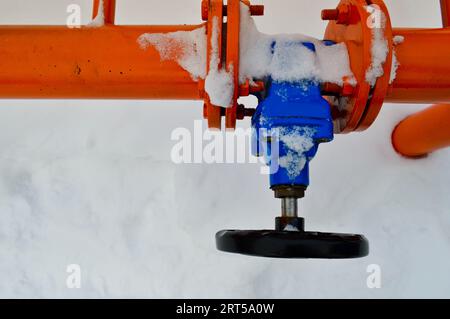Industrielle Abschaltvorrichtungen zur Regelung von Schutzrohrfittings. Schwarzes Ventil zum Öffnen und Schließen eines orangefarbenen Metallrohrs mit Flanschen, Bolzen und Muttern Stockfoto