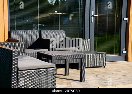 Relax Corner mit Gartenmöbeln auf der Terrasse des Hauses. Lounge-Zone im modernen Familienhaus Stockfoto