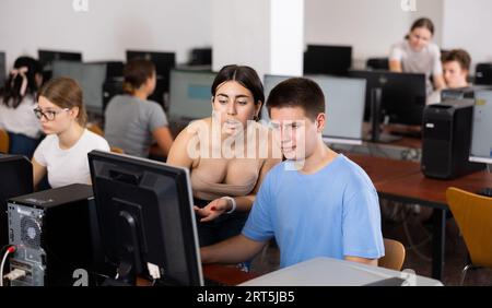Teenager-Mädchen hilft Freundin, Probleme am Computer in der Schule zu lösen Stockfoto