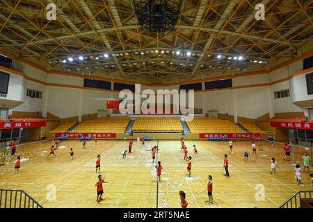 230908 -- PEKING, 8. September 2023 -- Kinder spielen Badminton im Ditan Gymnasium, das der Sportort für Gewichtheben bei den Peking 1990 Asiatischen Spielen in Peking, Hauptstadt von China, 21. August 2023 war. Hangzhou wird die dritte Stadt in China, die nach Peking 1990 und Guangzhou 2010 die Asienspiele ausrichtet. Einige Sportstätten, die für die Asienspiele in Peking und Guangzhou genutzt oder gebaut wurden, waren bereits nach ihrer Fertigstellung für die Öffentlichkeit zugänglich, was eine wichtige Rolle bei der Förderung der Massentätigkeit und der Anziehung von mehr Menschen zum Sport spielt. SPCHINA-ASIAN GAMES-VENUES-MASS FITNESS CN CHENXZHONGH Stockfoto