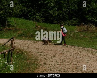 Eine tausendjährige Wanderin mit zwei Hunden und Rucksack in den Karpaten, auf dem Gipfel der Ukraine, ein europäisches Rucksacktouristen und Haustiere, Freunde auf landschaftlich reizvollen Landschaften Stockfoto