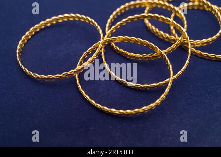 24k (24 Karat) Türkisch Gold Twist Armband steht in einem Haufen auf einem dunkelblauen Hintergrund im Goldladen Stockfoto