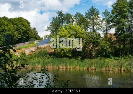 Kleines Solarkraftwerk mit Sonnenkollektoren in der Nähe von Wasser am Flussufer. Saubere Solarenergie, ökologisch, umweltfreundlich Stockfoto