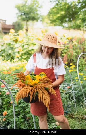 Ein Blumenbauer, der einen Herbstblumenstrauß aus ihrem Schnittfluss trägt Stockfoto