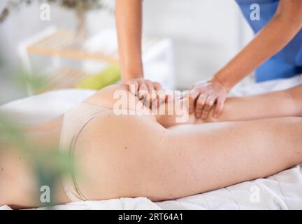 Professionelle Masseurin bei der Massage von Oberschenkel und Gesäß gegen Cellulite an die Frau Stockfoto
