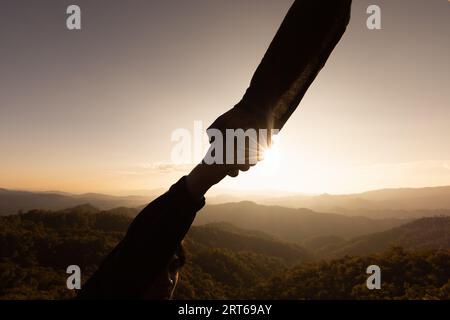 Silhouette des Erreichens, Helfens, Hoffen und Unterstützens einander über Sonnenuntergang Hintergrund, Hilfe, Hoffnung und Unterstützung einander über Sonnenuntergang Hintergrund Stockfoto