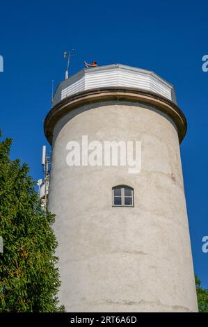 Ein Mädchen macht Fotos von der Spitze des alten, stillgelegten Leuchtturms, der in einer Waldwiese auf der schmalen Insel Jomfruland, Telemark, Norwegen, liegt. Stockfoto