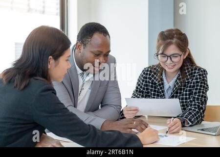 Multiethnische Kollegen sammeln sich in Vorstandssitzungen, um gemeinsam Finanzdokumente von Analysten und Unternehmen zu erstellen. Verschiedene Mitarbeiter bei Team-Office-Meetings Stockfoto