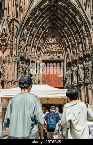 Straßburg, Frankreich - 7. Juli 2023: Straßburgs Kathedrale Notre-Dame bezaubert mit dieser unverwechselbaren Aussicht, während die Touristen von hinten ihre Pracht bestaunen Stockfoto