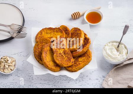 Süßer Kürbistoast mit Honig und Sahne, gestreut mit Puderzucker und Mandelblüten auf hellblauem, strukturiertem Hintergrund, Draufsicht. Köstliches Haus Stockfoto