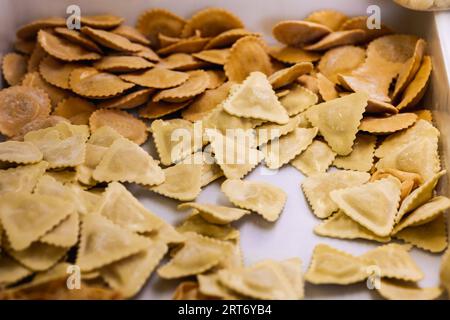 Von oben Nahaufnahme von ungekochten Pasta-Ravioli in verschiedenen Formen, die auf weißem Tisch verteilt sind Stockfoto