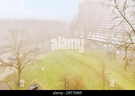 Außenansicht des Gebäudes in einem Wohnviertel in der Stadt unter bewölktem Himmel und Nebel in der Nähe des grünen Parks Stockfoto