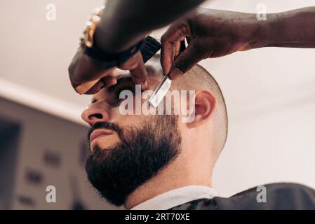 Ernten Sie anonymen professionellen Barbier-Rasierbart eines brutalen männlichen Klienten Stockfoto