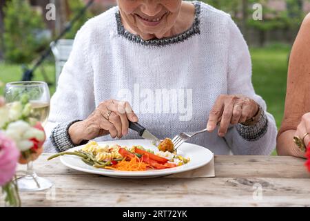 Junger afroamerikanischer Mann in einem leichten Pullover, der romantisch mit seinem Partner an einem gemütlichen Restauranttisch toast und einen besonderen Moment teilt. Stockfoto