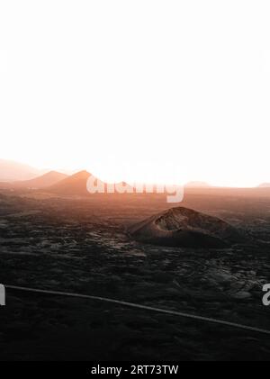 Landschaftsbild - Vulkane auf Lanzarote bei Sonnenuntergang. Moody and Dark Photo - Panorama der schwarzen Lavainsel Lanzarote. Stockfoto