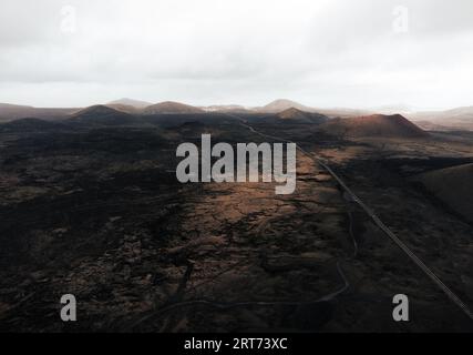 Dramatisches Landschaftsbild - Vulkane auf Lanzarote bei Sonnenuntergang. Moody and Dark Photo - Panorama der schwarzen Lavainsel Lanzarote. Stockfoto
