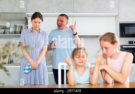 Eltern streiten sich hinter dem Rücken verschwommener, unerkennbarer Kindertöchter. Stockfoto