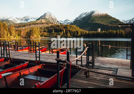 Rote Boote im Hafen, die im Herbst in der Hochtatra (Slowakei) in der Strbske pleso am See begrenzt werden. Wunderschöner und farbenfroher Sonnenaufgang auf dem See mit B Stockfoto
