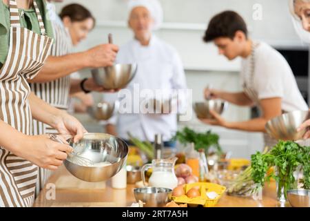 Metallschale mit Sauce, die von den Händen der jungen Frau gemischt wird Stockfoto